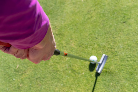 A young woman tees off on fairways, smiling in sunlight, confident swing flowing with the breeze,...