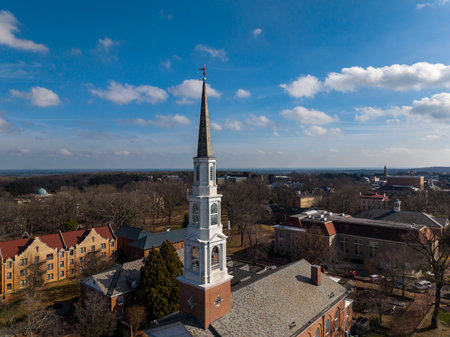 Aerial view of the Morehead-Patterson Bell Tower rises 172 feet above manicured lawns and hedges at UNC Chapel Hill, its Roman numeral clock faces and conical spire marking a timeless campus landmark.のeditorial素材