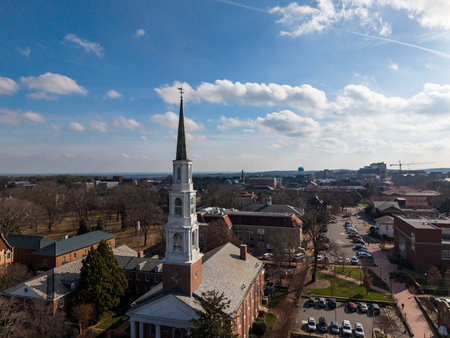 Aerial view of the Morehead-Patterson Bell Tower rises 172 feet above manicured lawns and hedges at UNC Chapel Hill, its Roman numeral clock faces and conical spire marking a timeless campus landmark.の写真素材