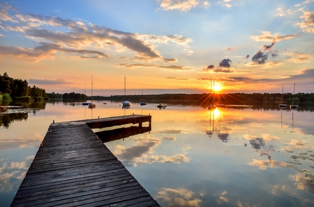 Summer afternoon landscape. Wooden pier and boat on the water at sunset.の写真素材