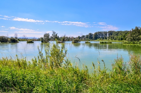 Sunny summer landscape. Beautiful pond in the countryside with mountains in the background.の写真素材