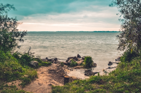 Beautiful cloudy summer landscape. Lovely beach on the lake.の写真素材