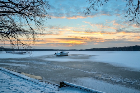 Afternoon winter landscape. Boat on a frozen lake.の写真素材