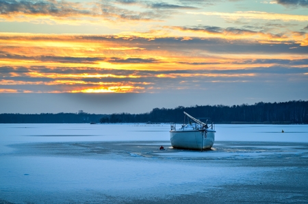 Afternoon winter landscape. Boat on a frozen lake.の写真素材