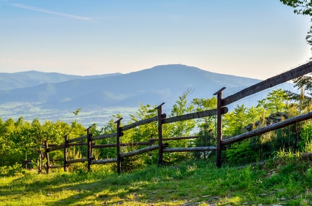 Beautiful rural landscape. Clearing with a wooden fence overlooking the mountains.の写真素材