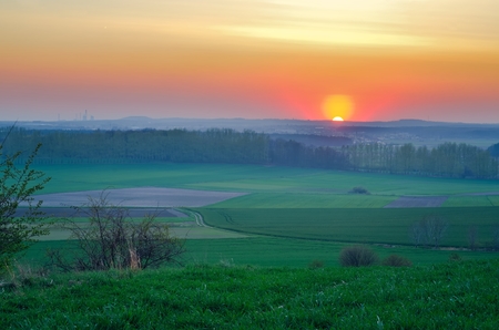 Fabulous spring evening landscape. Beautiful sunset over green meadows.の写真素材