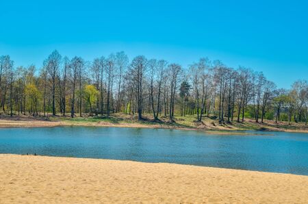 Beautiful spring landscape. Empty beach by the lake on a sunny day.の写真素材