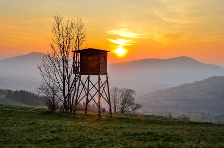 Beautiful mountain colorful landscape. Hunting pulpit and the setting sun over the hills.の写真素材