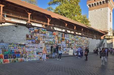 KRAKOW, POLAND - OCTOBER 13, 2018: Tourists at the stand with paintings on the market in Krakow, Poland.のeditorial素材