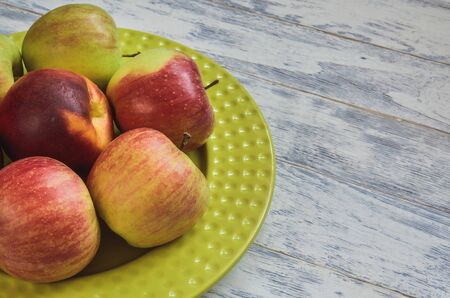 Fresh red fruits. Apples on a green plate on a wooden background.の写真素材