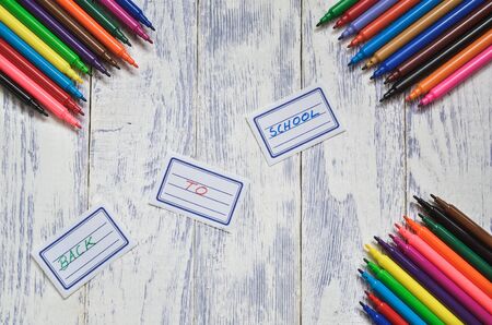 Creative concept with school supplies. Labels with back to school text and markers on a wooden desk.の写真素材