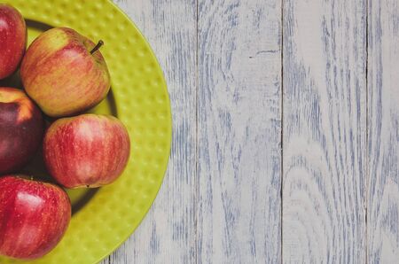 Fresh red fruits. Apples on a green plate on a wooden background.の写真素材