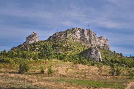 Sunny summer landscape. Beautiful rocks with a cross at the top.の写真素材