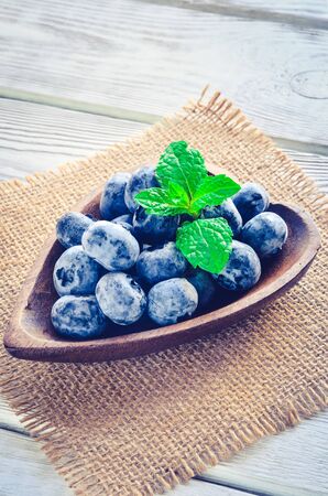 Fresh purple fruits. Juicy blueberries in a wooden dish.の写真素材