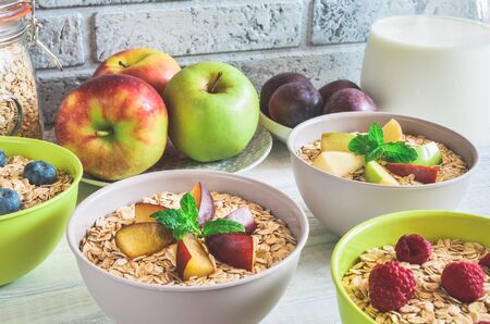 Sweet delicious healthy breakfast. Porridge with apples, plums, raspberries and blueberries on the kitchen table.の写真素材