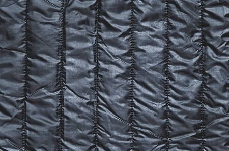 Shiny clothing background. Black background from quilted material.の写真素材