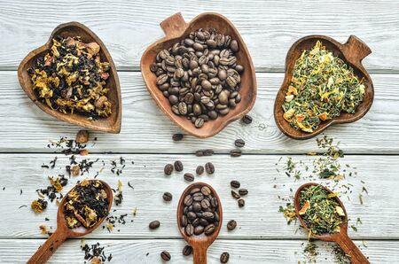 Interesting concept with a selection of drinks. Coffee beans, fruit tea and herbs on a wooden table.の写真素材