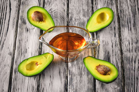 Natural fruit oil. A glass of oil and avocado fruit.の写真素材