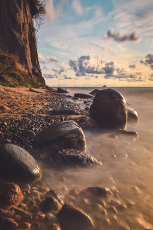 Beautiful morning seaside landscape. Stones in a blurry sea. Photo with long exposure effect.
