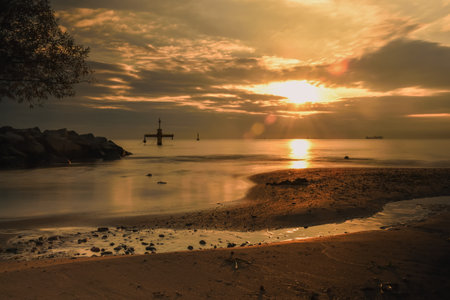 Beautiful sunrise by the sea. The sun reflecting off the talfi water on the sandy beach. A photo with the effect of a long exposure.の写真素材