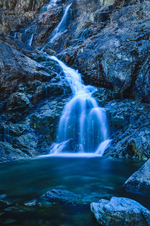 Beautiful waterfall with blurred water effect. Photo taken in the Valley of Five Ponds in the Polish Tatra Mountains. long-exposure photo.の写真素材