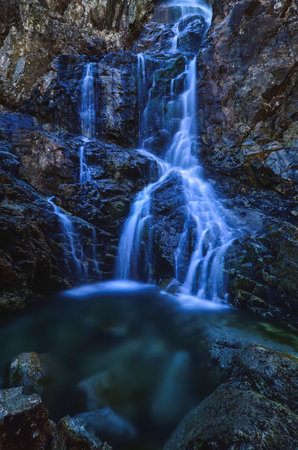 Beautiful waterfall with blurred water effect. Photo taken in the Valley of Five Ponds in the Polish Tatra Mountains. long-exposure photo.の写真素材