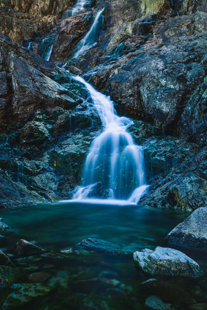 Beautiful waterfall with blurred water effect. Photo taken in the Valley of Five Ponds in the Polish Tatra Mountains. long-exposure photo.の写真素材