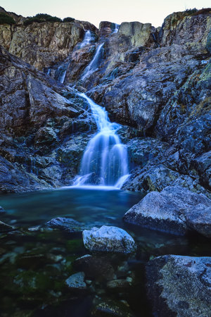 Beautiful waterfall with blurred water effect. Photo taken in the Valley of Five Ponds in the Polish Tatra Mountains. long-exposure photo.の写真素材