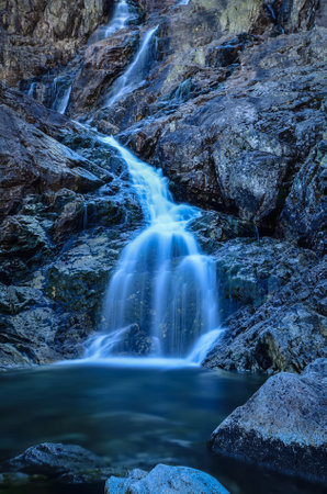Beautiful waterfall with blurred water effect. Photo taken in the Valley of Five Ponds in the Polish Tatra Mountains. long-exposure photo.の写真素材