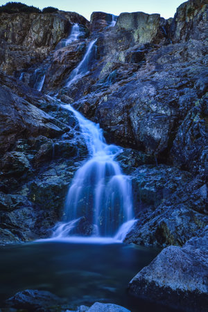 Beautiful waterfall with blurred water effect. Photo taken in the Valley of Five Ponds in the Polish Tatra Mountains. long-exposure photo.の写真素材