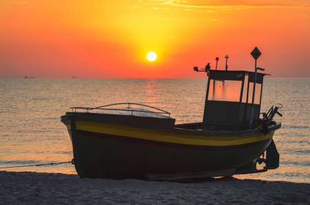 Colorful morning landscape by the sea. Beautiful boat on the beach with the rising sun. Photo taken in Gdynia, Poland.の写真素材
