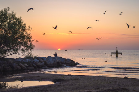 Beautiful summer morning landscape by the sea. Sunrise and the silhouette of a girl against the background of the rising sun. Photo taken in Gdynia, Poland.の写真素材