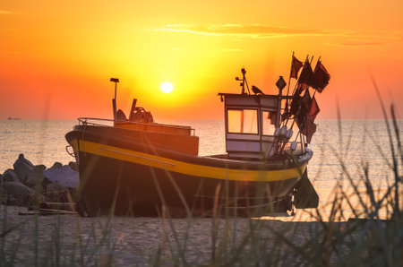 Colorful morning landscape by the sea. Beautiful boat on the beach with the rising sun. Photo taken in Gdynia, Poland.の写真素材
