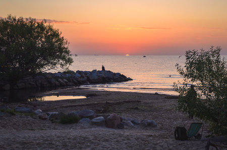Beautiful summer morning landscape by the sea. Sunrise and the silhouette of a girl against the background of the rising sun. Photo taken in Gdynia, Poland.の写真素材