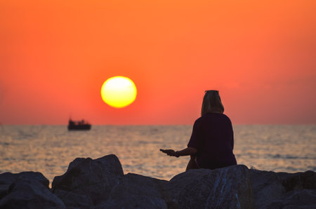 The concept of a silhouette of a girl at sunrise over the sea. Photo taken on the beach in Gdynia, Poland.の写真素材