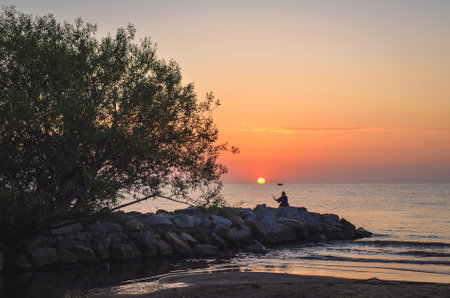 Beautiful summer morning landscape by the sea. Sunrise and the silhouette of a girl against the background of the rising sun. Photo taken in Gdynia, Poland.の写真素材