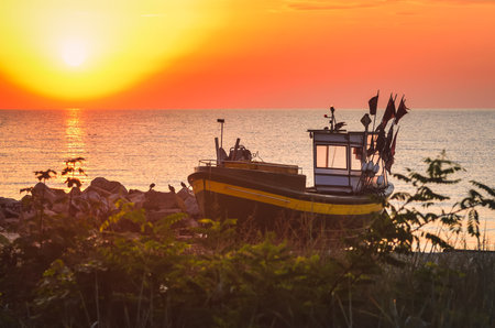 Colorful morning landscape by the sea. Beautiful boat on the beach with the rising sun. Photo taken in Gdynia, Poland.の写真素材