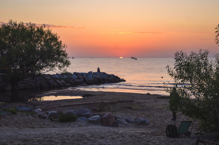 Beautiful summer morning landscape by the sea. Sunrise and the silhouette of a girl against the background of the rising sun. Photo taken in Gdynia, Poland.の写真素材