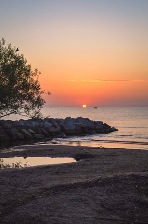 Beautiful summer morning landscape by the sea. Sunrise and the silhouette of a girl against the background of the rising sun. Photo taken in Gdynia, Poland.の写真素材