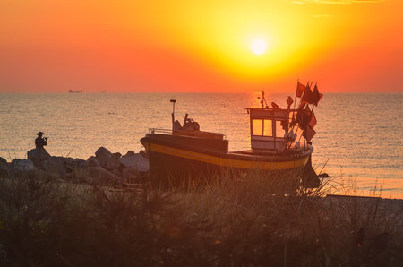 Colorful morning landscape by the sea. Beautiful boat on the beach with the rising sun. Photo taken in Gdynia, Poland.の写真素材