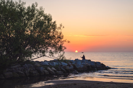 Beautiful summer morning landscape by the sea. Sunrise and the silhouette of a girl against the background of the rising sun. Photo taken in Gdynia, Poland.の写真素材