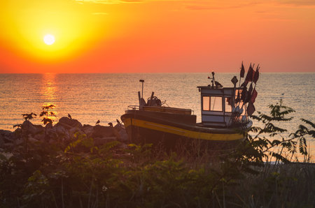 Colorful morning landscape by the sea. Beautiful boat on the beach with the rising sun. Photo taken in Gdynia, Poland.の写真素材