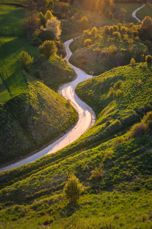 Beautiful spring landscape among green hills. Charming winding road between green nature. Photo taken in Grodzisko - Stradow, Poland.の写真素材