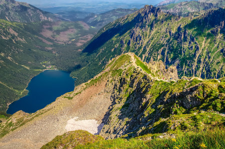 Lake and ridge in polish mountains in summer scenery. Morskie Oko (Eye of the Sea) and trail leading via a exposed ridge section, called Kazalnica, High Tatra Mountains, Poland.の写真素材