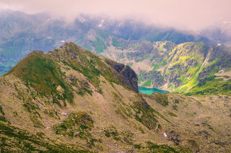 Mountain landscape in cloudy summer scenery. Picturesque view stretches over mountain ridge in clouds and trail running down to the valley. High Tatra Mountains in Poland.の写真素材