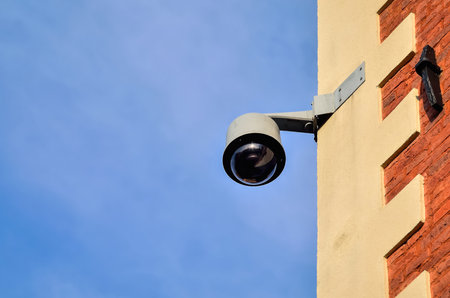 Municipal monitoring on the wall of the tenement house. Security camera on building against a blue sky background.の写真素材