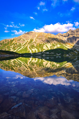 Beautiful summer mountain landscape by the lake. View of the mountains reflecting in the water at Czarny Staw Gasienicowy in the Polish High Tatras.の写真素材