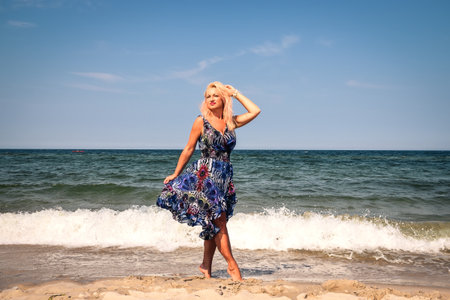 Feminine session on the beach on a beautiful sunny day. Girl with blonde hair and a colorful dress by the Polish Baltic Sea.の写真素材