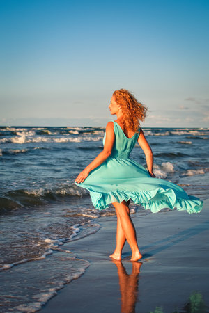 Beautiful blonde woman on a sandy beach. Photo taken on the Baltic Sea in Leba, Poland. Photo with a shallow depth of field with blurred background.の写真素材