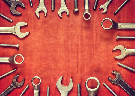 Screw and wrenches frame. Wrenches, screw and ring spanners in several different sizes on natural wooden background.の写真素材